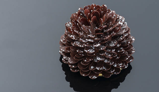 「ジンジャーブレッド パインコーン」<br>クリスマスツリーに飾る松ぼっくりのオーナメントからインスピレーションを受けたケーキ。ナツメグの香り高いケーキ生地に、ジンジャー風味のキャラメルクリームを挟み、チョコレートでコーティング。60以上のパーツから生みだされるケーキの見た目は、雪化粧をした松ぼっくりと瓜ふたつ。その完成度の高さに食べ方を躊躇うほどだ。