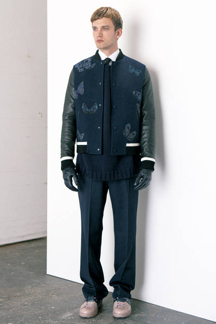 ベーシックアイテムであるスタジャンに、クチュリエの技術を注ぎ込んだバタフライの刺しゅうをあしらい、あたらしいエレガンスを追求。トップスはシャツとオーバーサイズニットをレイヤードし、ボトムスはややワイドなシルエットのドローコード付きパンツでリラックス感を表現。<br><br>  ブルゾン50万7600円、パンツ11万9880円、ニット8万1000円、シャツ6万480円、タイ2万4840円（ヴァレンティノ)<br> グローブ3万4560円、シューズ8万2080円（ヴァレンティノ ガラヴァーニ／阪急メンズ大阪2階、阪急メンズ東京2階）