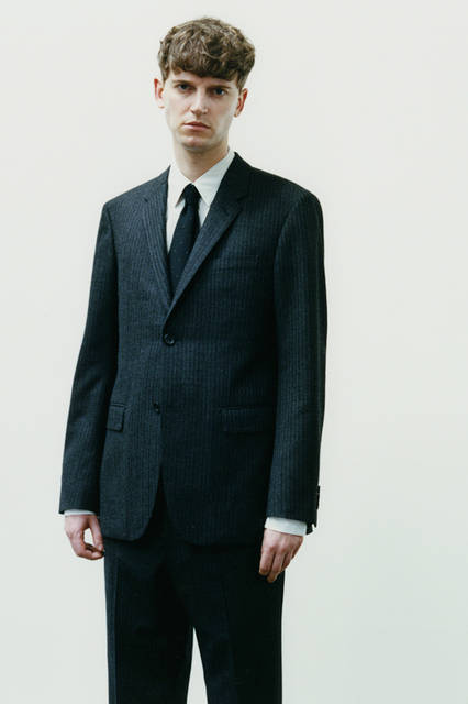 「ラバット」社の「FINE MERINO DOUBLE STRIPE」は、チャコールグレーのベースに極細のライトグレーのステッチが上品さを演出。ほどよい起毛感が秋冬シーズンらしい表情をつくる。定番のシルエットのドレスシャツとドットネクタイが、オーセンティックな雰囲気を醸し出す。ジャケット9万720円、シャツ3万2400円、トラウザーズ4万6440円、ネクタイ1万6200円（すべてマーガレット・ハウエル）