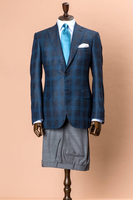 上質なシルク混素材を使ったジャケットは、体型やオケージョンを選ばないベストセラーモデルのブルニコ。鮮やかなブルーのチェックが立体的に施され、グレーのパンツと合わせた王道的なジャケパンスタイルも新鮮な印象。 <br /><br /> ジャケット69万2280円（阪急メンズ先行販売）、パンツ8万4240円、シャツ7万1280円、タイ3万240円、チーフ1万9440円／ブリオーニ＜阪急メンズ大阪3階・阪急メンズ東京3階＞