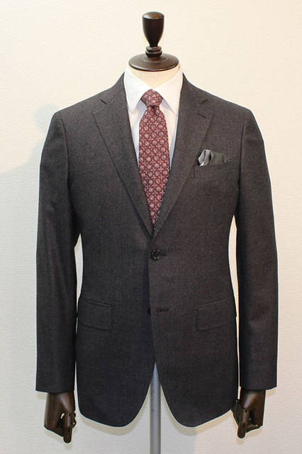 <strong>D'URBAN｜ダーバン</strong><br />2015-16年秋冬コレクション　SUPER140'S糸を使用した上質なフランネル素材のスーツ。ボルドーのカラー糸が表面に現れるカラーミックスが新鮮。無地調ブラウンのフランネルスーツにレッドのブロック柄ネクタイ、白無地シャツ、グレー×ブラックのチーフはパフというコーディネート。スーツ12万4200円