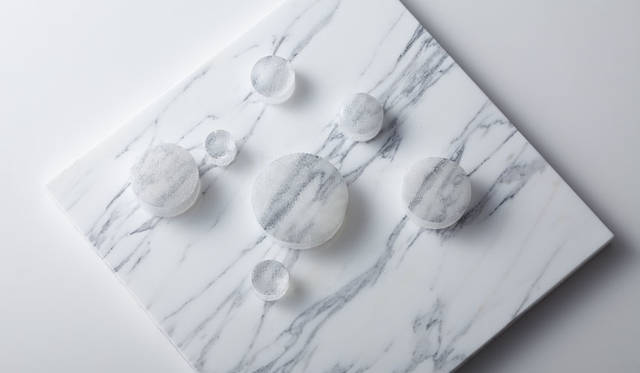 「OPTICAL FIBER BLOCK」 Designed by Shinya Yoshida　ウレキサイト（テレビ石）とおなじ結晶構造をもつ光ファイバー製ブロック。遥か彼方まで情報を伝達できる光ファイバーの光学特性を生かして、触れたテクスチャーの色情報が表面に伝達される。その現象はまるで触れたものに擬態するかのよう。光ファイバー1本＝1ピクセルとなり、抽象化された色情報はデジタルに変換されたような不思議な表情を見せる。成形後は切削加工と研磨も可能なため、あらゆるプロダクトや建築への応用が可能だ