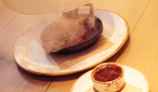 蓋をとると、煙のなかから鶏の手羽先が顔をだす「Smoky Wings」（14米ドル）