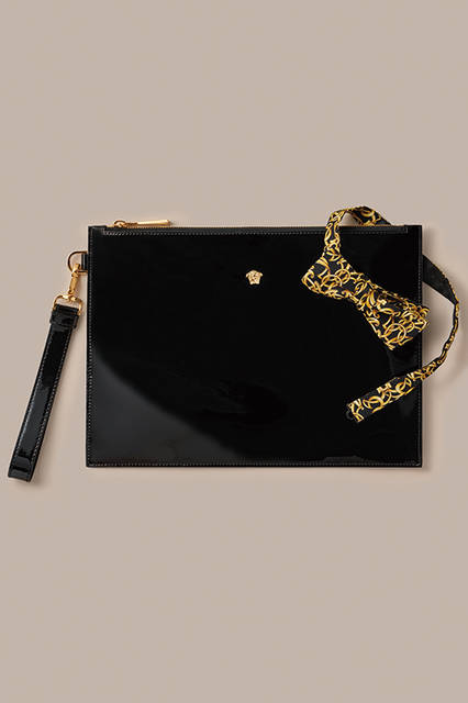 インパクトのあるパテントレザーのクラッチは、ファスナー部分にメドゥーサの意匠をあしらったゴールドパーツがアクセントに。ボウタイは、ヴェルサーチらしいバロック柄で、ドレスアップのキーアイテムとして活躍してくれる。<br><br>クラッチバッグ[W31×H22cm]6万1560円（阪急メンズ限定販売）、ボウタイ2万3760円（阪急メンズ先行販売）／ヴェルサーチ ＜阪急メンズ大阪3階・阪急メンズ東京2階＞