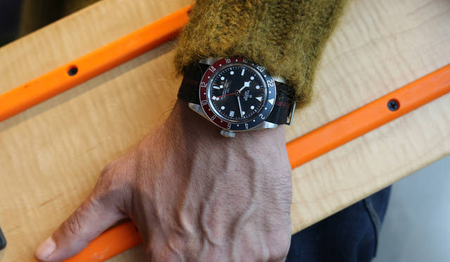バーゼルワールド2018で発表された「GMT」は、1950年代製のダイバーズウォッチにインスピレーションを得たデザイン。チューダーが製造するキャリブレーションに新しい機能を導入した自社製のキャリバーMT5652を採用している。GMTの象徴ともいえるバーガンディとブルーの２色のベゼルは、時差を超えて世界を飛び回るエグゼクティブにぴったりなデザインとして人気だが、あえてカジュアルな装いに自然となじませた。「スーツにGMTって、一昔前はすごくイメージがあったけど、チューダーはクラシックだし、今の時代ならもっとラフに使いこなすほうが粋では。これは村上さんから撮影前に「着てみたい」と逆指名を受けた＜ヤンチェ_オンテンバール＞のチェックコート。鮮やかな＜マルニ＞のニットとロングマフラーも、カジュアルを意識しました。ベゼルと同配色のNATOストラップにすることで、ステンレスのブレスよりも全体を落ち着かせてみました」。<BR>デニムパンツ3万6000円（JANTJE_ONTEMBAAR／ヤンチェ_オンテンバール 03-6812-7106）　ニット14万5000円、マフラー（参考色）7万7000円（すべてMARNI／マルニジャパン 03-6416-1024）ブーツ3万5000円（HUNTER／ハンター 0120-563-567）※コートはスタイリスト私物