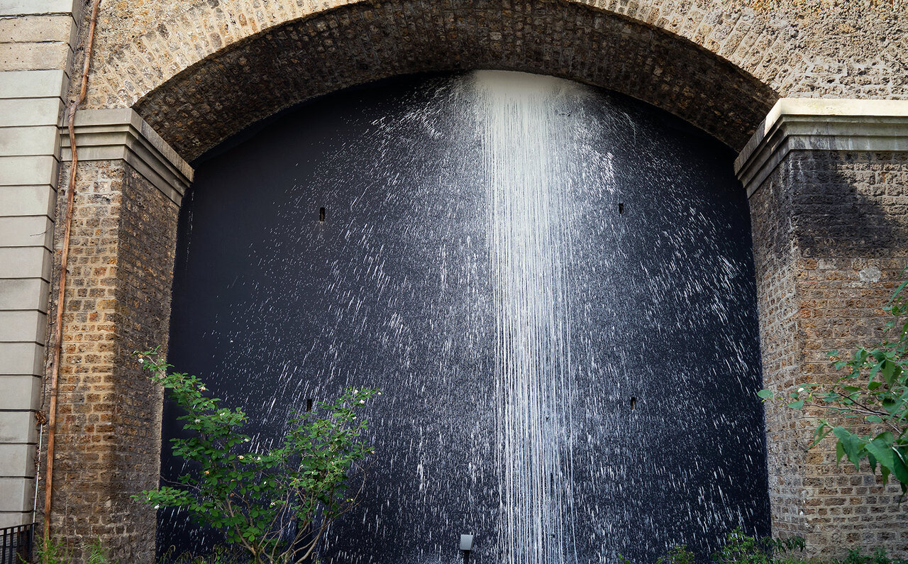 KRは、古い石で築かれた高さ10mの壁面に流れ落ちる滝のようなペイントを施した。